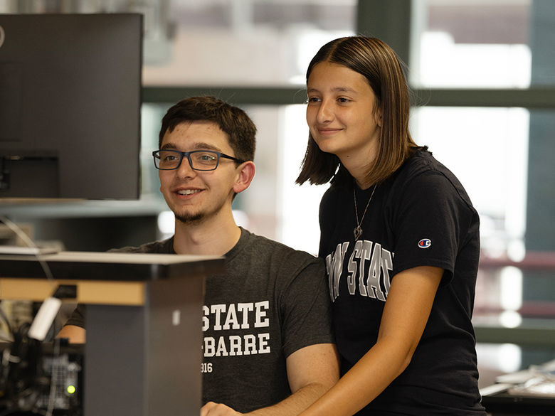 a male student and female student working together side by side in front of a computer screen